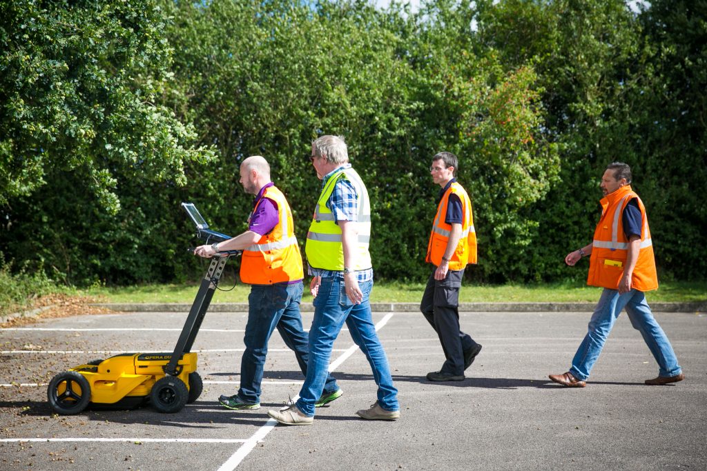 Men walking in hi vis with yellow machine